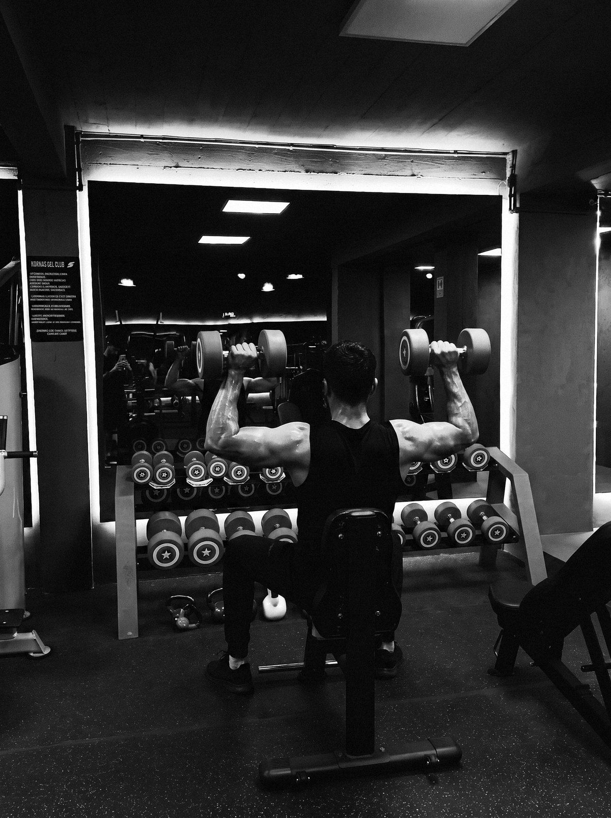 Press de hombros con mancuernas frente al rack del club